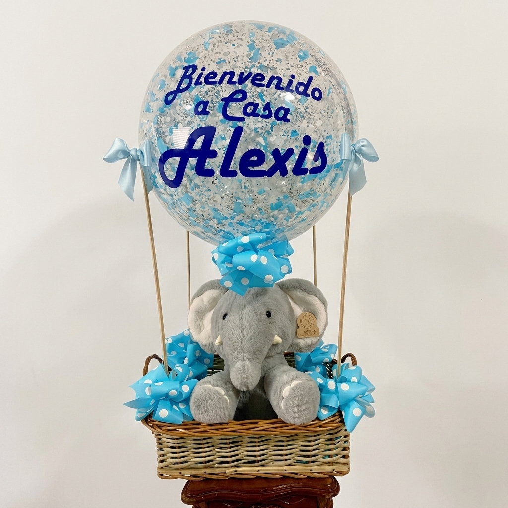 Canasta con peluche de elefante, moños azules y globo personalizado.